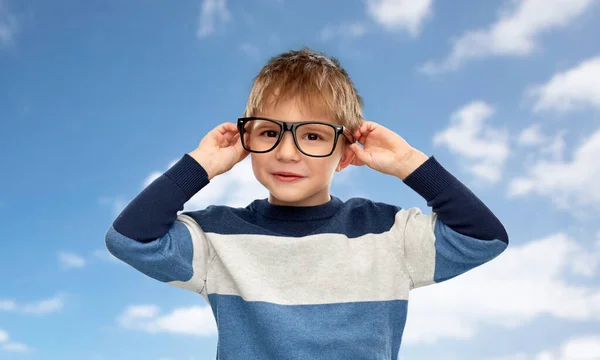 Portrait of smiling little boy in glasses over sky — Stock Photo, Image
