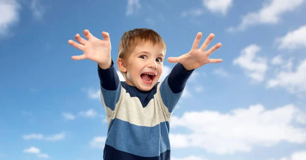 Маленький мальчик делает страшные лица на фоне неба — стоковое фото
