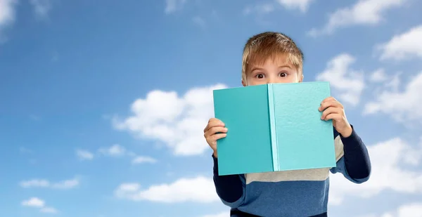 Liten pojke gömmer sig över boken över himlen — Stockfoto