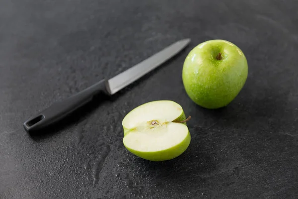 Зеленые яблоки и кухонный нож на фоне шифера — стоковое фото