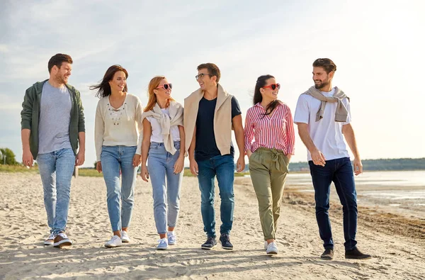 Amigos felizes andando ao longo da praia de verão — Fotografia de Stock