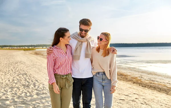 Glada vänner promenader längs sommarstranden — Stockfoto