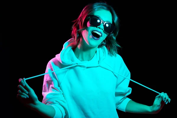 Frau trägt Kapuzenpullover im Neonlicht über Schwarz — Stockfoto