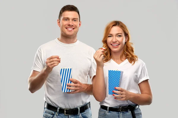 Happy couple in white t-shirts eating popcorn — Stock Photo, Image
