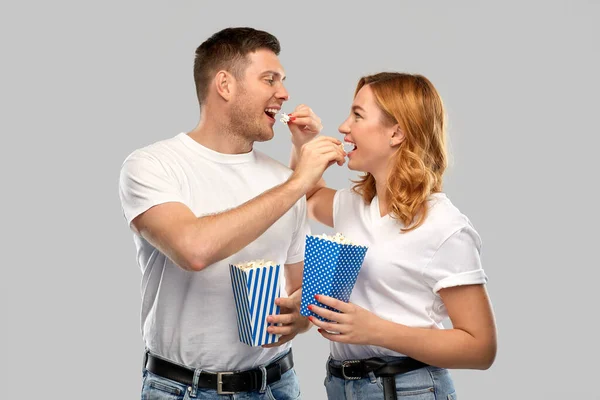 Happy couple in white t-shirts eating popcorn — Stock Photo, Image