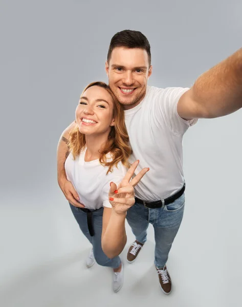 Couple heureux en t-shirts blancs prenant selfie — Photo