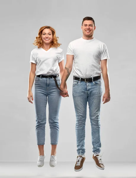 Feliz pareja en blanco camisetas saltando o colgando —  Fotos de Stock