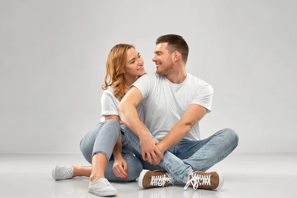 Feliz pareja en blanco camisetas sentado en el suelo —  Fotos de Stock