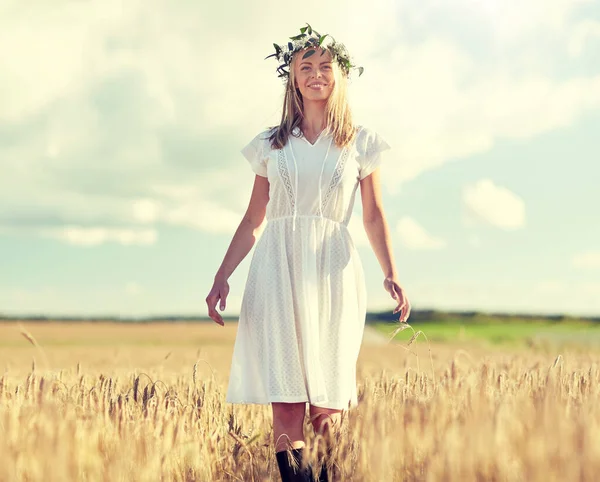 Счастливая молодая женщина в цветочном венке на зерновом поле — стоковое фото