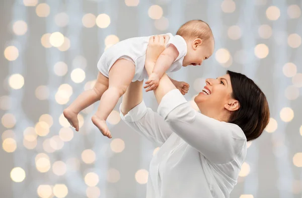 Feliz mãe de meia-idade com bebê sobre luzes — Fotografia de Stock