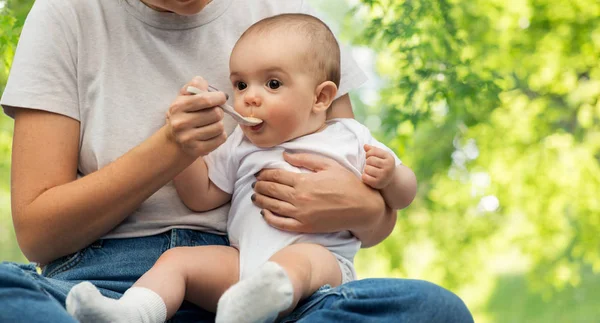 Close up de mãe com colher alimentando pequeno bebê — Fotografia de Stock