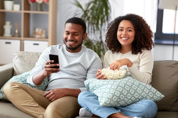 Coppia africana con popcorn guardando la tv a casa — Foto Stock