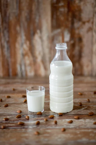 Milk and almonds on wooden table — Stock Photo, Image