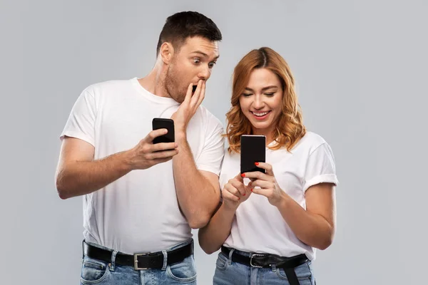 Glückliches Paar in weißen T-Shirts mit Smartphones — Stockfoto