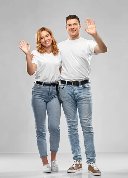 Boldog pár fehér pólóban integető kézzel — Stock Fotó