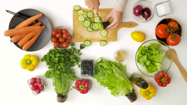 Young woman chopping cucumber for salad at home — Stock Video