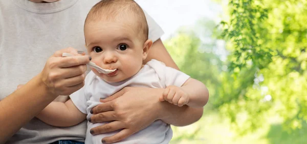 Primer plano de la madre con cuchara alimentando al pequeño bebé — Foto de Stock