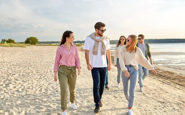 Amici felici passeggiando lungo la spiaggia estiva — Foto Stock