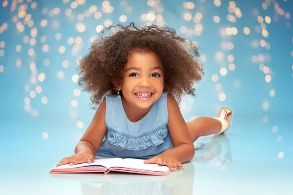 Усміхнена маленька афроамериканська дівчинка читає книгу — стокове фото