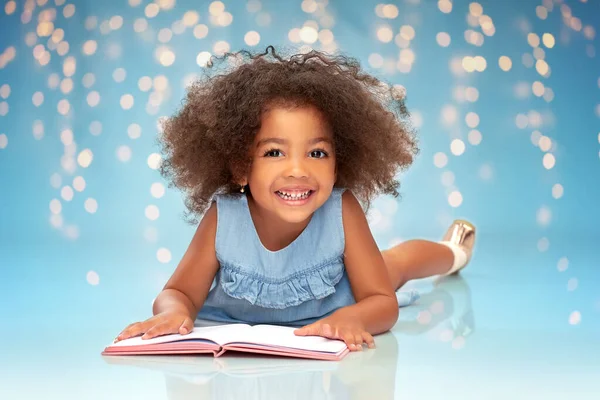 Sonriente poco afroamericano chica leyendo libro — Foto de Stock