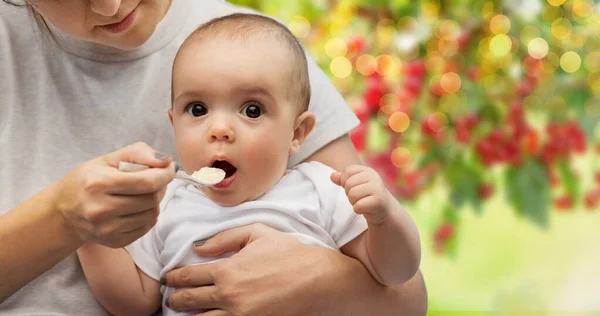 Close up de mãe com colher alimentando pequeno bebê — Fotografia de Stock