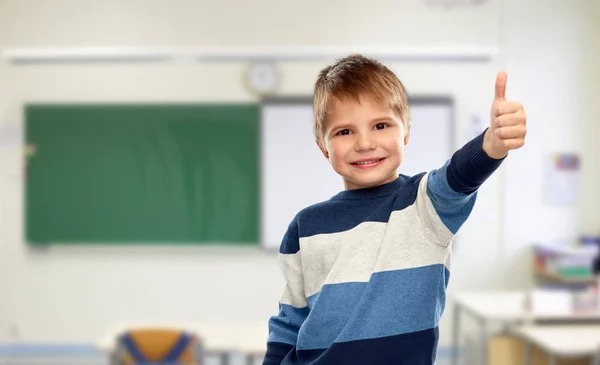 Niño pequeño mostrando pulgares hacia arriba en la escuela —  Fotos de Stock