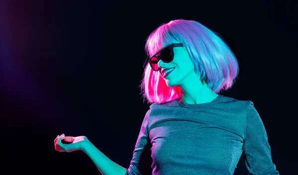 Mujer feliz en peluca rosa y gafas de sol bailando — Foto de Stock