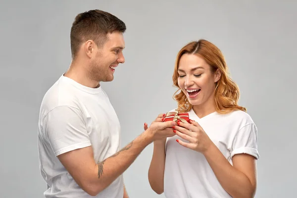 Glückliches Paar in weißen T-Shirts mit Weihnachtsgeschenk — Stockfoto