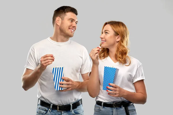 Feliz pareja en blanco camisetas comer palomitas de maíz — Foto de Stock