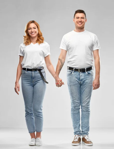 Счастливая пара в белых футболках, держащаяся за руки — стоковое фото