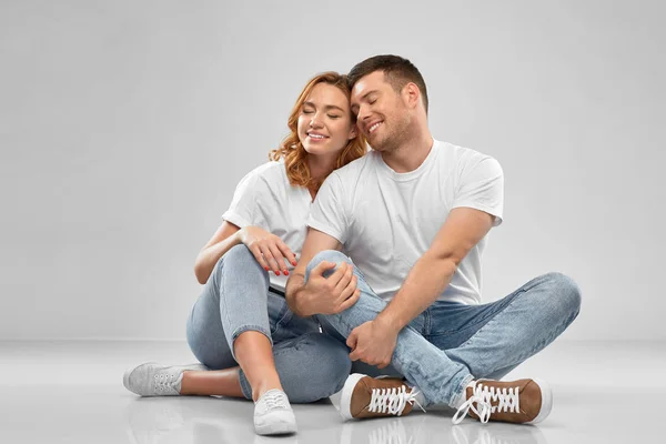 Heureux couple en t-shirts blancs assis sur le sol — Photo