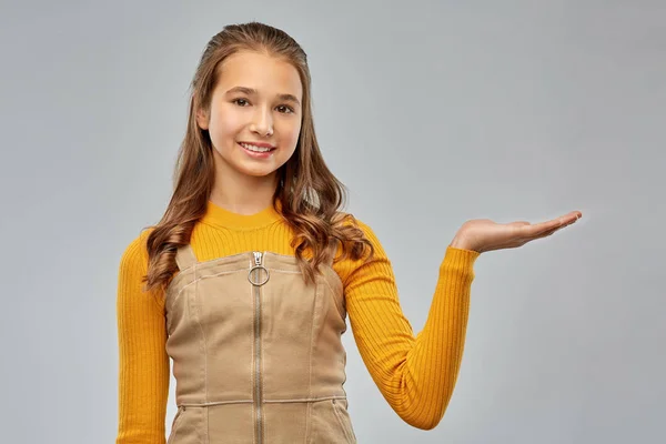 Szczęśliwy nastolatek dziewczyna trzyma coś na pustej ręce — Zdjęcie stockowe