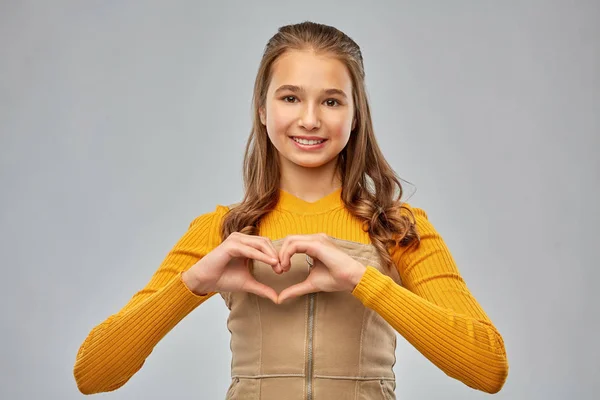 Усміхнена дівчина-підліток робить серце рукою — стокове фото