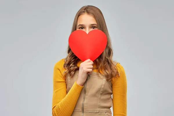 Souriant adolescent fille se cachant sur rouge coeur — Photo