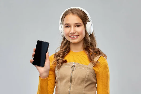 Kulaklıklı genç kız akıllı telefon gösteriyor. — Stok fotoğraf