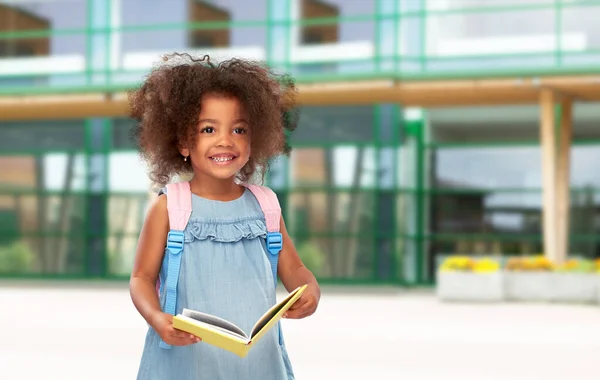 Gelukkig klein Afrikaans meisje met boek en rugzak — Stockfoto