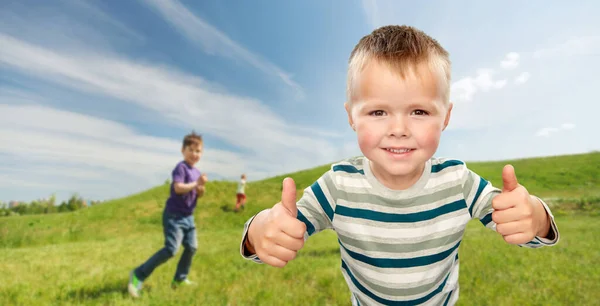 Усміхнений хлопчик показує великі пальці на відкритому повітрі — стокове фото