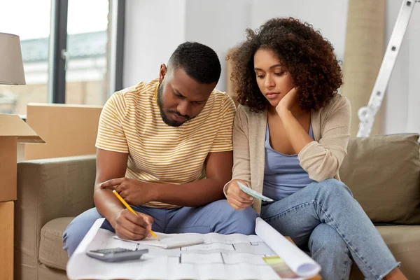 Sad couple with blueprint counting money at home — Stock Photo, Image