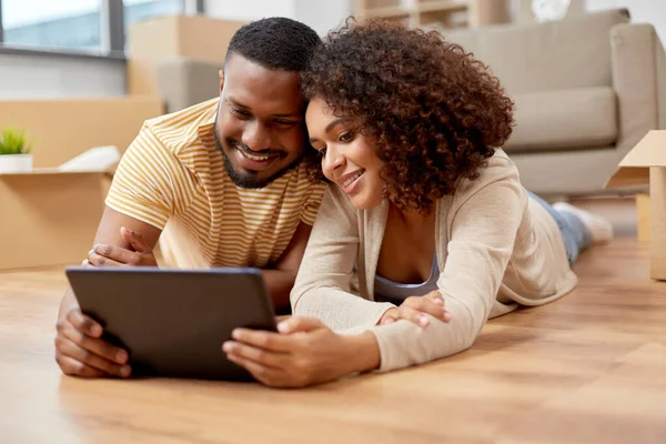 Casal feliz com computador tablet pc em nova casa — Fotografia de Stock