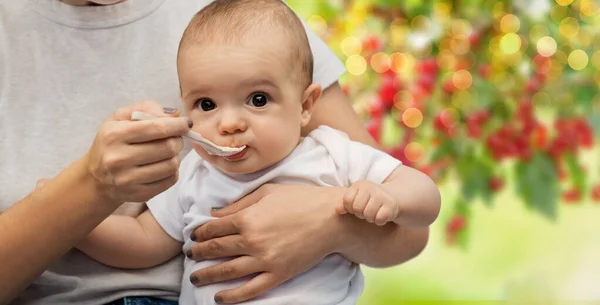Close up de mãe com colher alimentando pequeno bebê — Fotografia de Stock