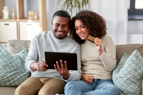 Pareja con tablet pc y tarjeta de crédito en casa — Foto de Stock