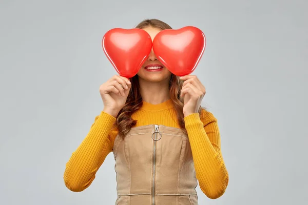 Menina adolescente feliz com balões em forma de coração vermelho — Fotografia de Stock