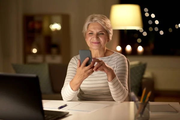 Seniorin nachts mit Smartphone zu Hause — Stockfoto