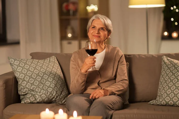 Senior woman drinking red wine at home in evening — Stock Photo, Image