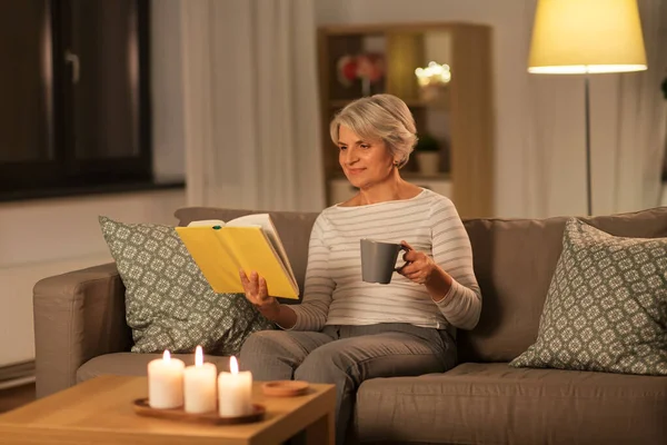 Starsza kobieta czyta książki i pije herbatę w domu — Zdjęcie stockowe