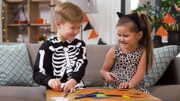 Kinderen in halloween kostuums doen ambachten thuis — Stockvideo