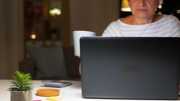 Seniorin mit Laptop trinkt zu Hause Kaffee — Stockvideo