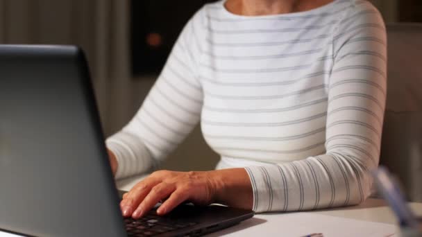 Счастливая пожилая женщина с ноутбуком дома вечером — стоковое видео
