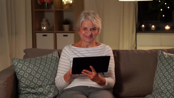 Mulher sênior feliz com tablet pc em casa à noite — Vídeo de Stock