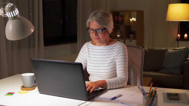 Mulher sênior feliz com laptop em casa à noite — Vídeo de Stock